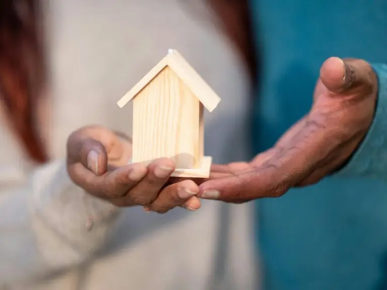 Two people holding a wooden house model