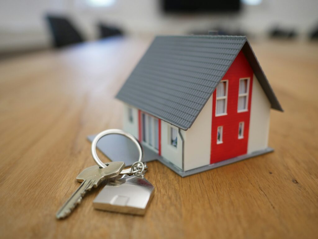 a small red and white house model and a set of keys on a wooden table
